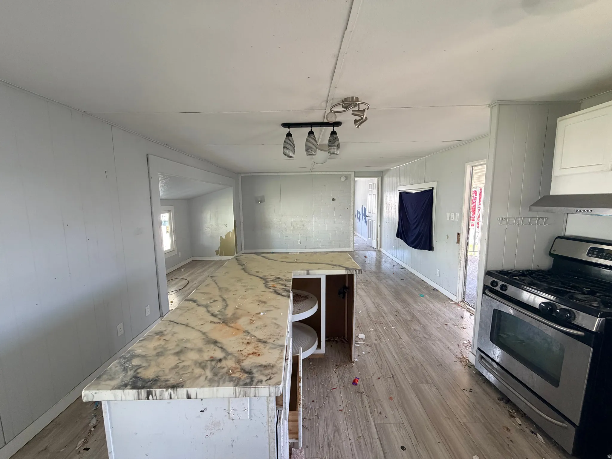 Kitchen area featuring an island with a light-toned countertop, a stainless steel range, and a coordinating range hood