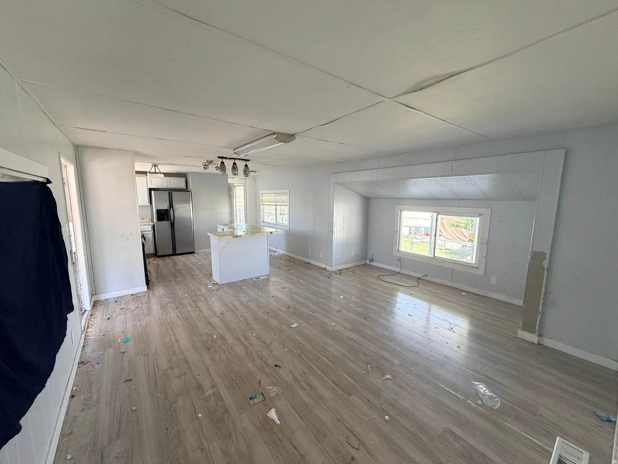 Open-concept living area featuring wood-finish flooring, white paneled walls, and multiple windows