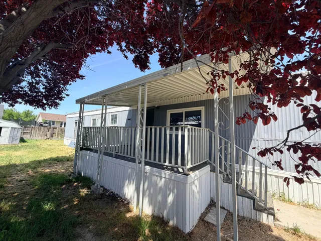 Exterior featuring a covered porch with metal railings, a grey siding facade, and a white skirting
