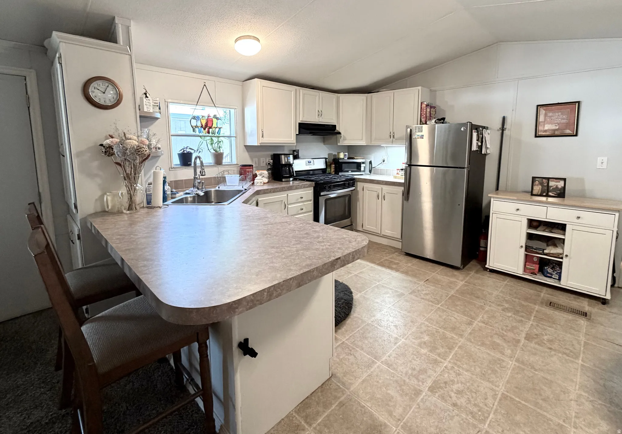 Large, open kitchen featuring peninsula with countertop seating, plenty of counter and cabinet space, stainless appliances, large pantry