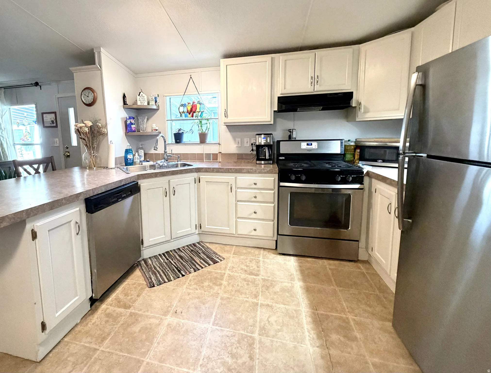 Large, open kitchen featuring peninsula with countertop seating, plenty of counter and cabinet space, stainless appliances, large pantry