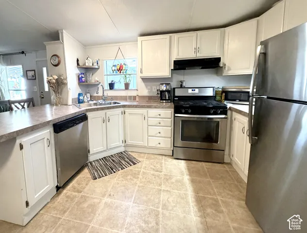 Large, open kitchen featuring peninsula with countertop seating, plenty of counter and cabinet space, stainless appliances, large pantry