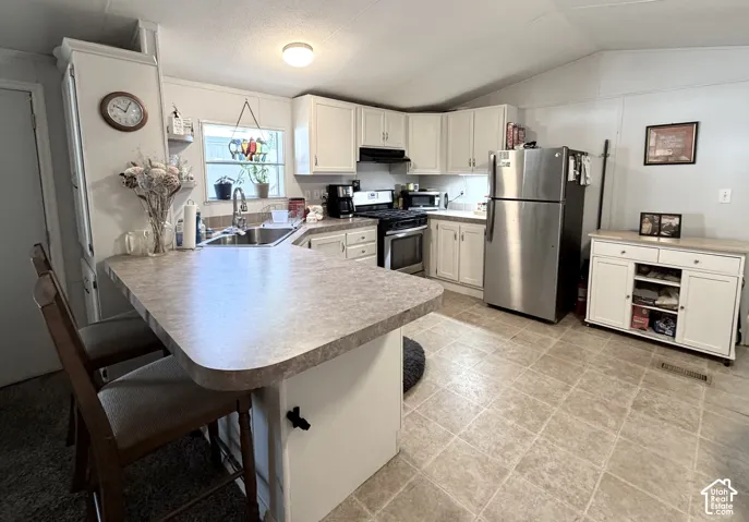 Large, open kitchen featuring peninsula with countertop seating, plenty of counter and cabinet space, stainless appliances, large pantry