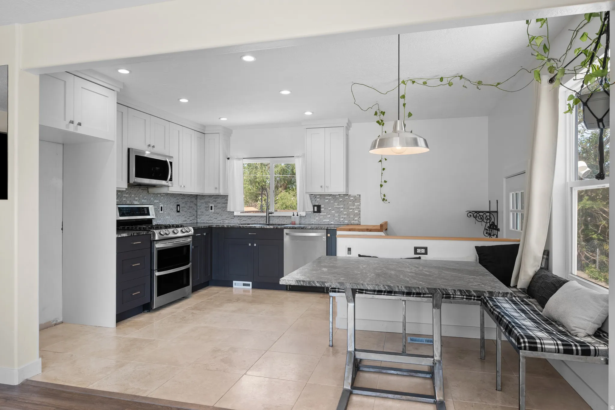 Modern kitchen featuring two-tone cabinetry, stainless steel appliances, and a tiled backsplash