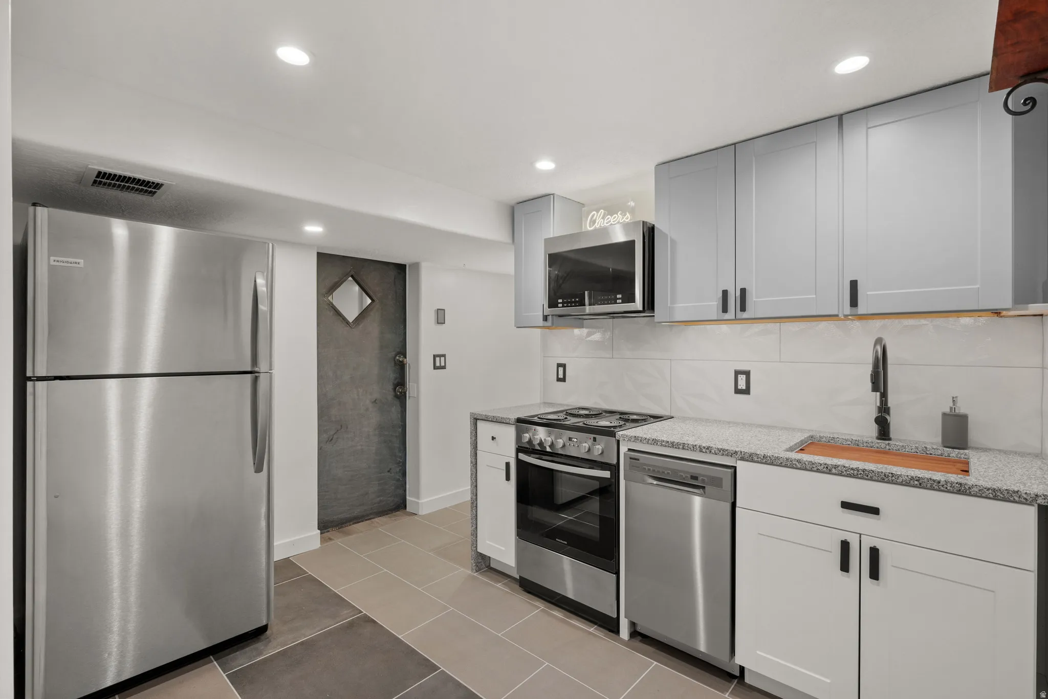 Modern kitchen featuring light gray upper cabinetry and white lower cabinetry with matte black hardware