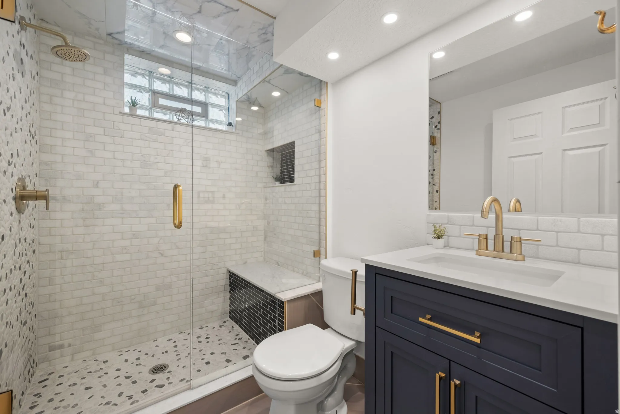 Modern bathroom featuring a glass-enclosed shower with subway tile surround and a built-in bench