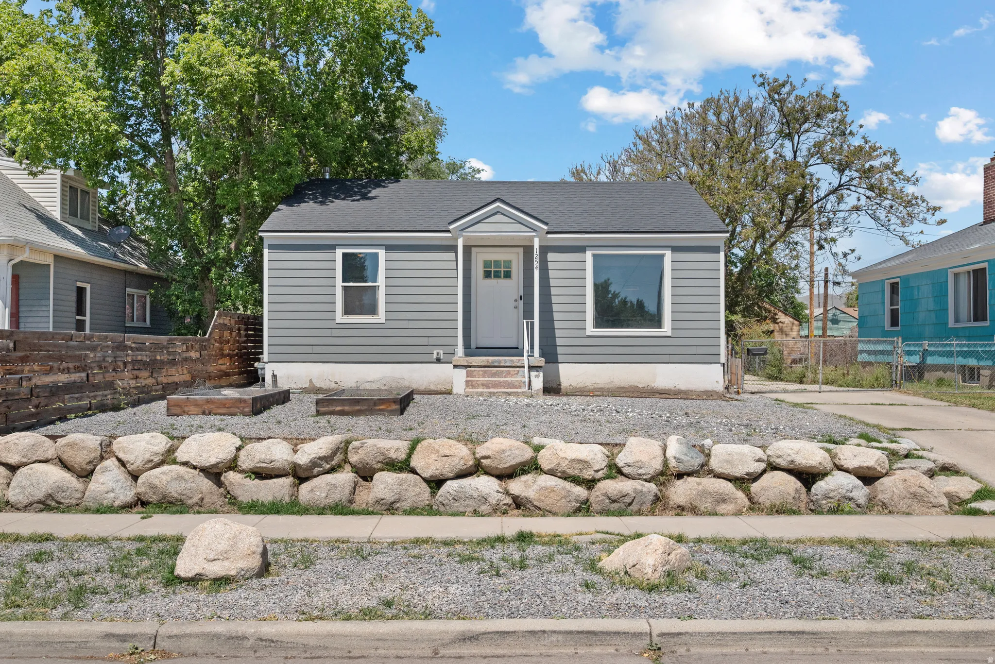 Charming bungalow with gray siding and a dark shingle roof