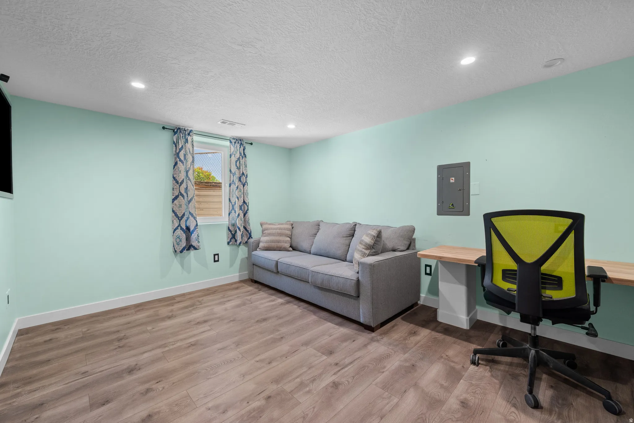 Spacious room featuring wood-finish flooring, recessed lighting, and a built-in wood desk with a support column