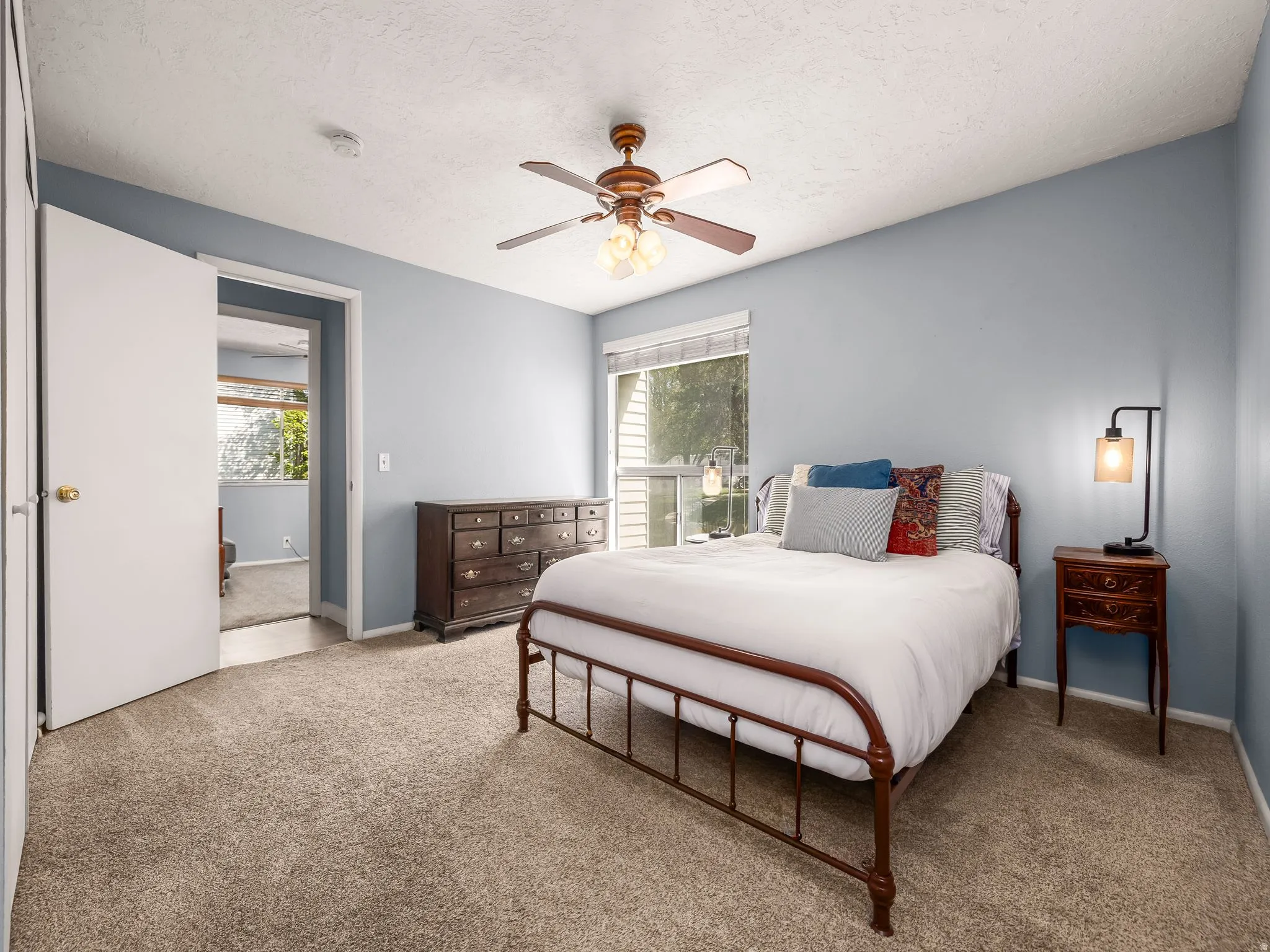 Bedroom featuring neutral-toned carpet flooring, light blue walls, and a ceiling fan with integrated lighting