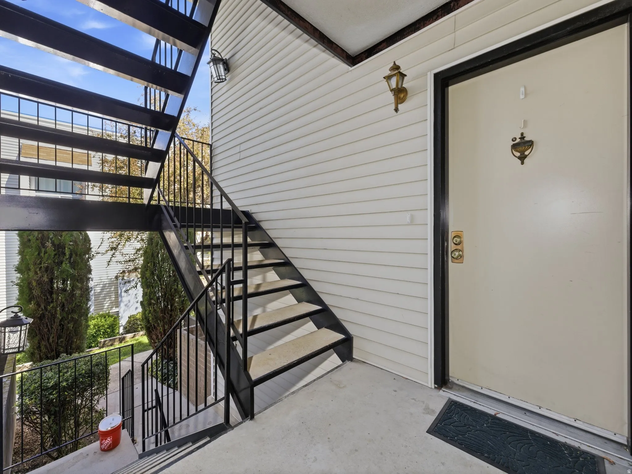 Cream-colored entry door with brass hardware and exterior sconce lighting