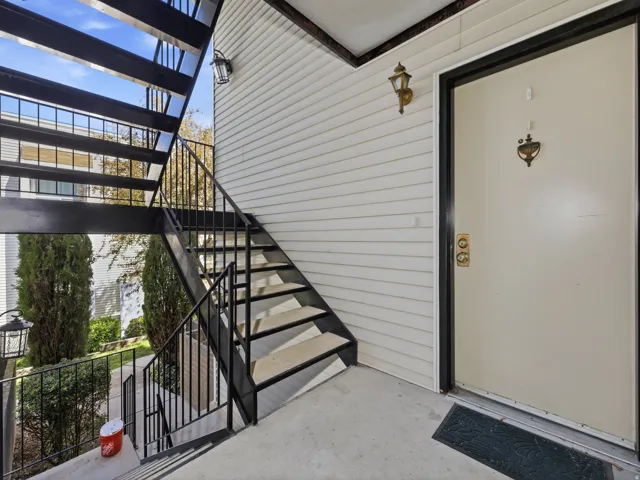 Cream-colored entry door with brass hardware and exterior sconce lighting