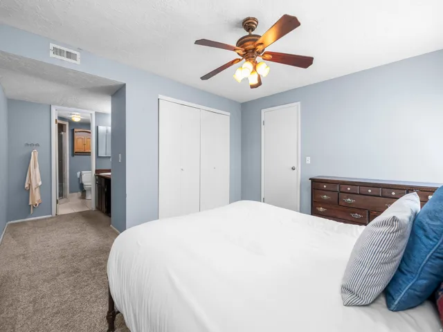 Bedroom featuring light blue walls, gray carpeting, and a ceiling fan with integrated lighting