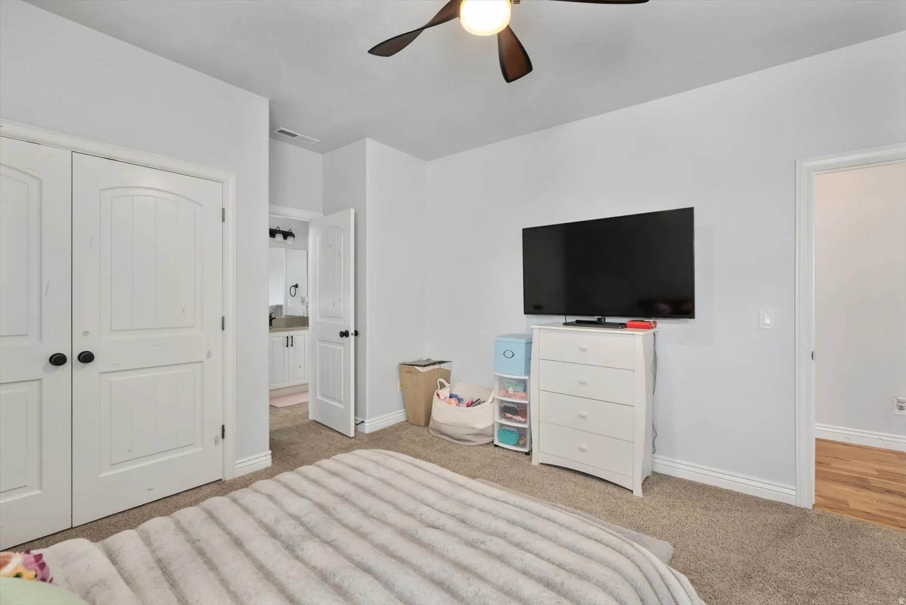 Carpeted bedroom featuring a ceiling fan with integrated lighting, white walls, and white trim