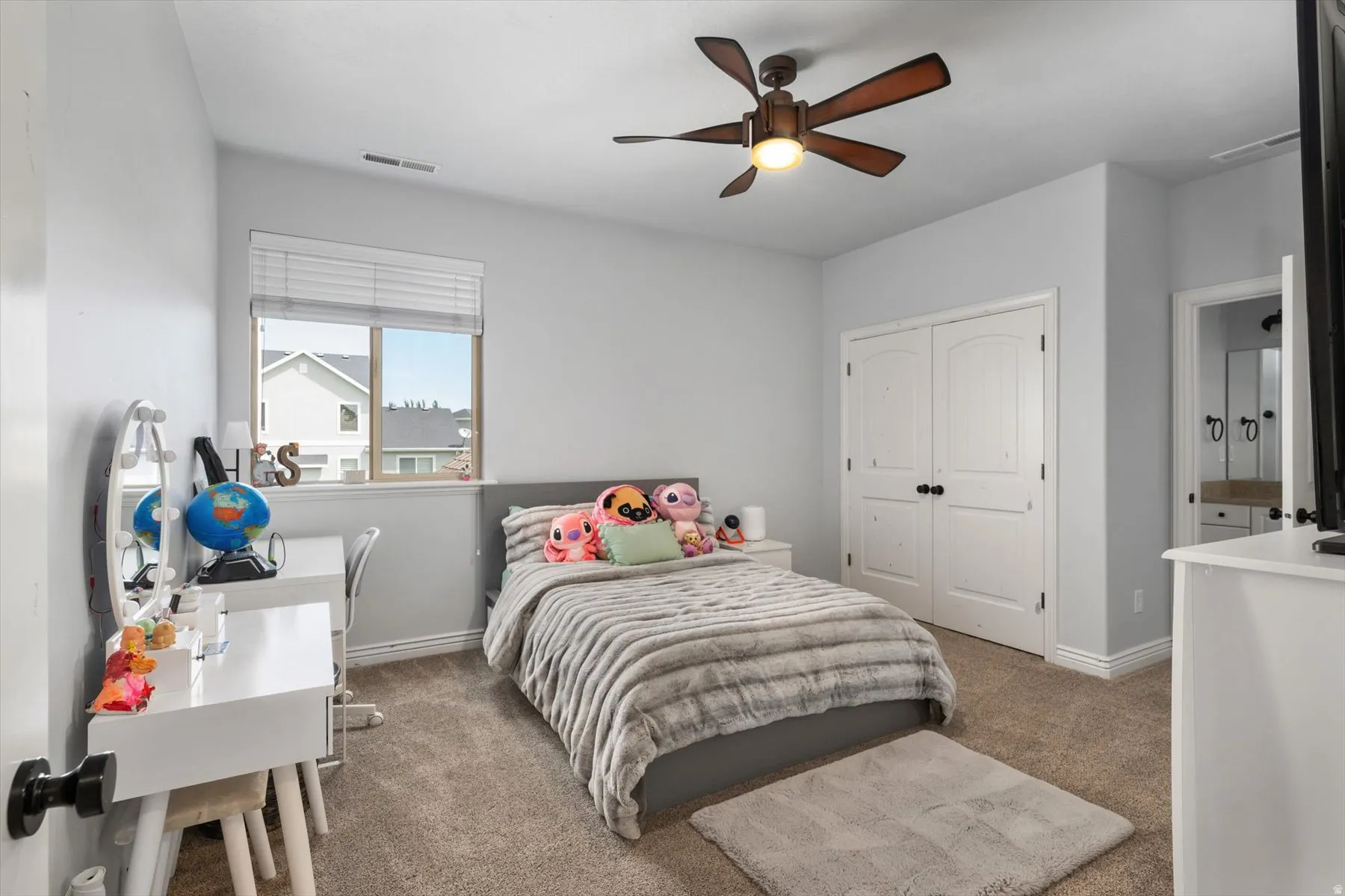 Carpeted bedroom featuring a ceiling fan, a window with blinds, and white double closet doors