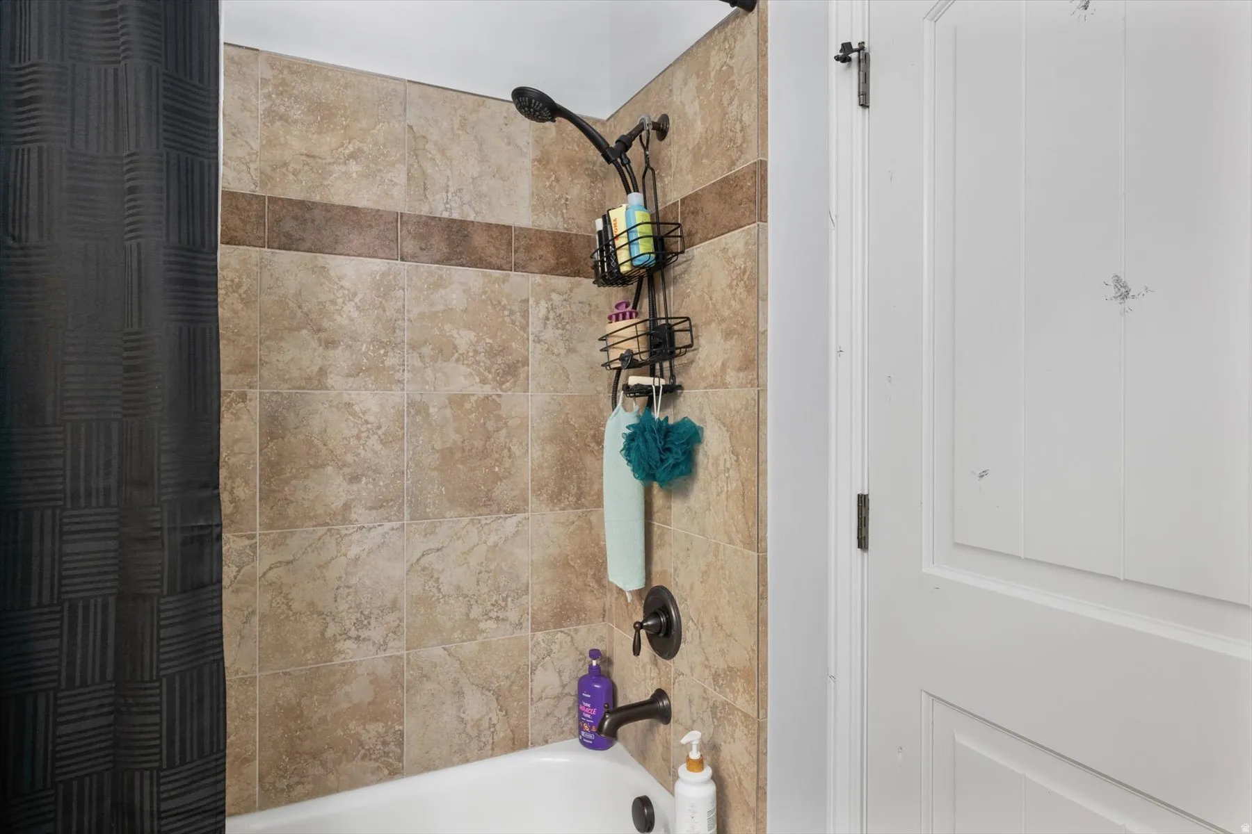 Full Bathroom with tub and shower combination featuring earth-toned tile surround with a decorative accent band and oil-rubbed bronze fixtures