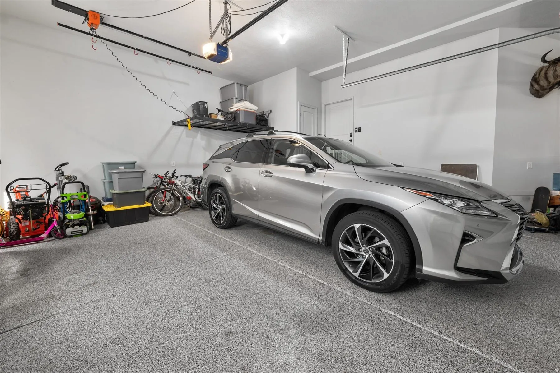 Spacious garage featuring a durable epoxy-coated floor, ample wall-mounted storage shelving, and a built-in garage door opener