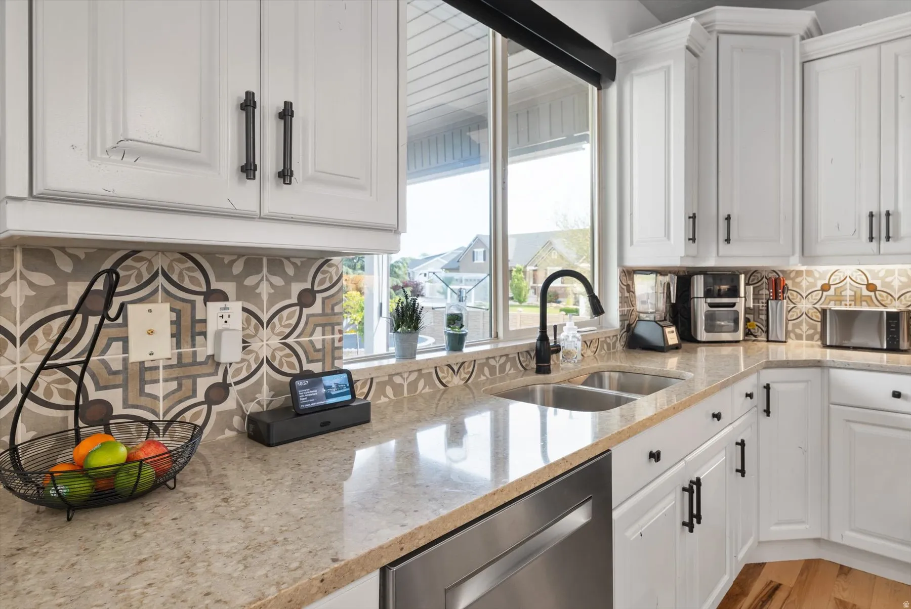 White cabinetry with black hardware, light speckled countertops, and a patterned backsplash