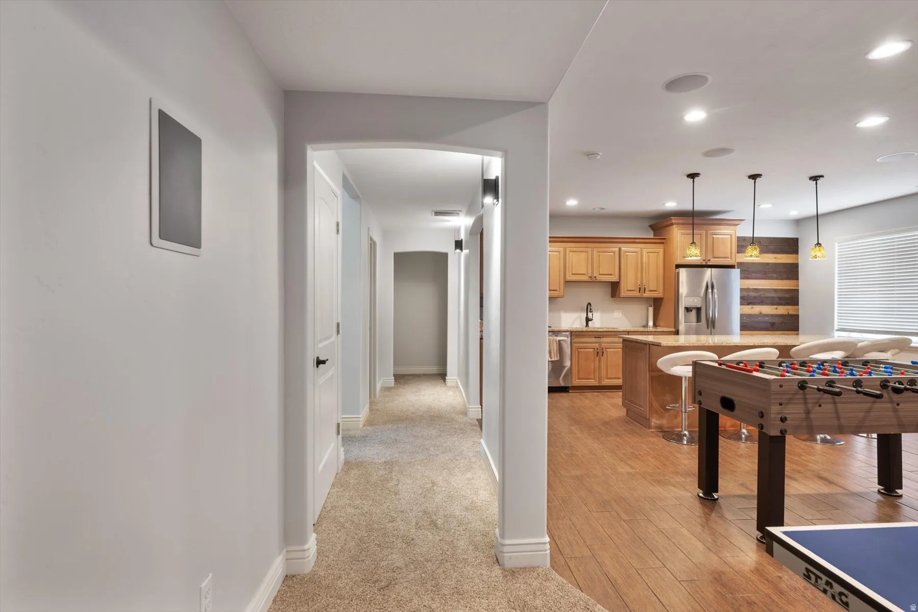 Open-concept living area with wood-finish flooring, recessed lighting, and a full kitchen