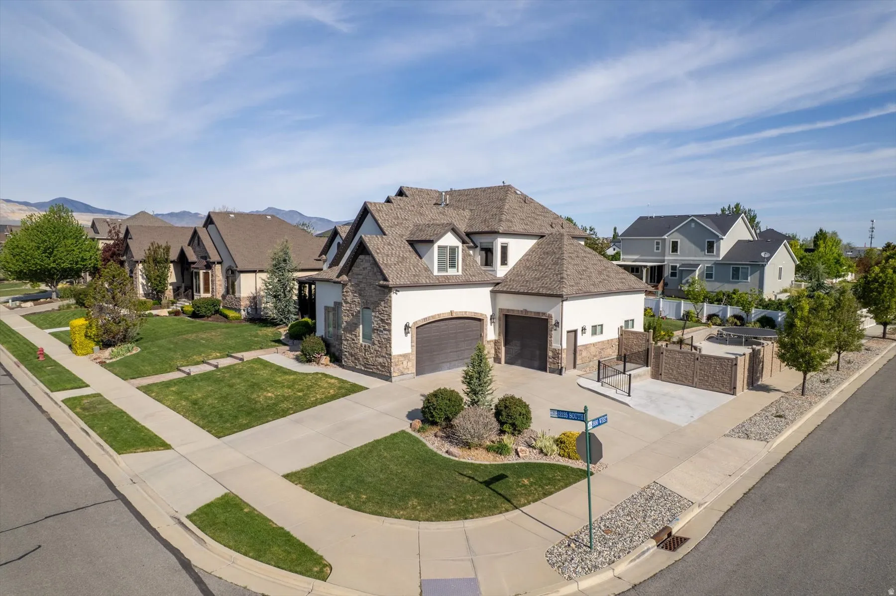 Corner lot residence featuring a multi-tone stone and stucco exterior, a two-car garage, and a separate single-car garage