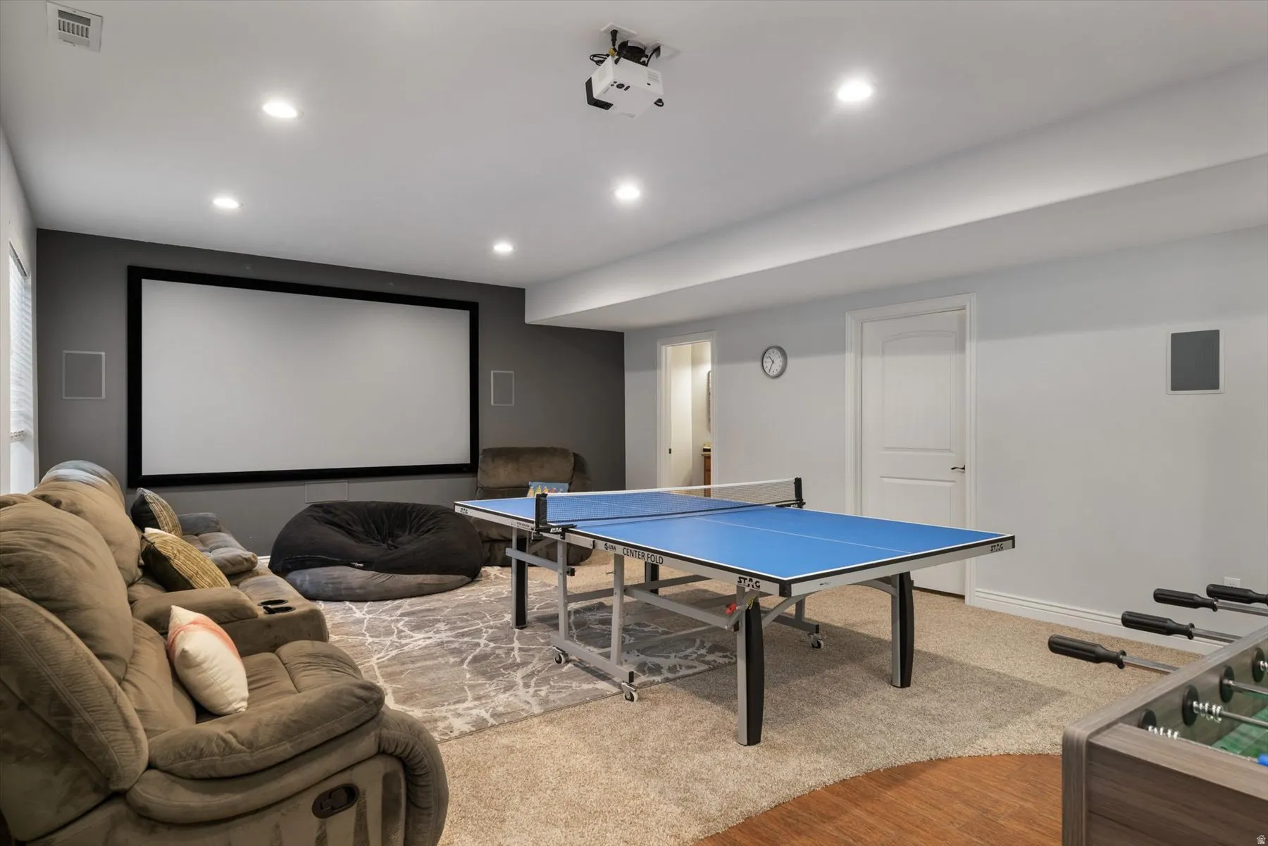Dedicated entertainment room featuring a large projection screen, recessed lighting, and a neutral color palette
