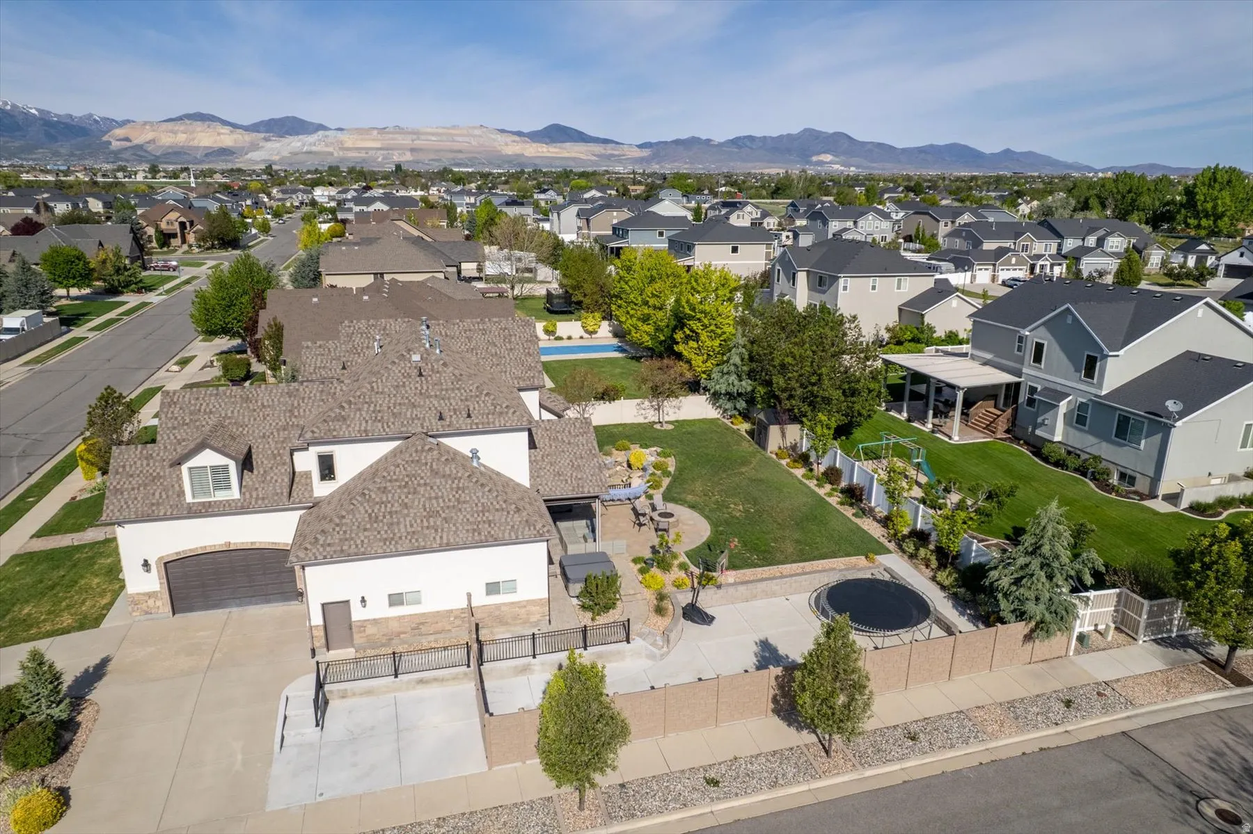 Expansive backyard featuring a manicured lawn, established landscaping, and a patio area