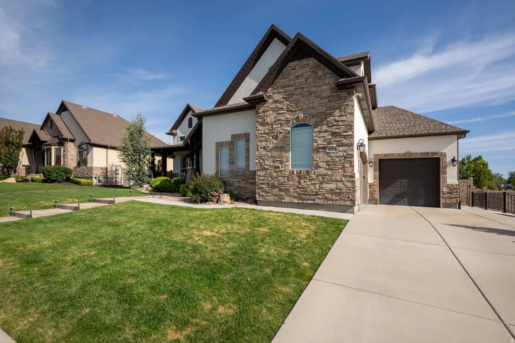 Exterior featuring stone and stucco finishes, a dark brown garage door, and a concrete driveway