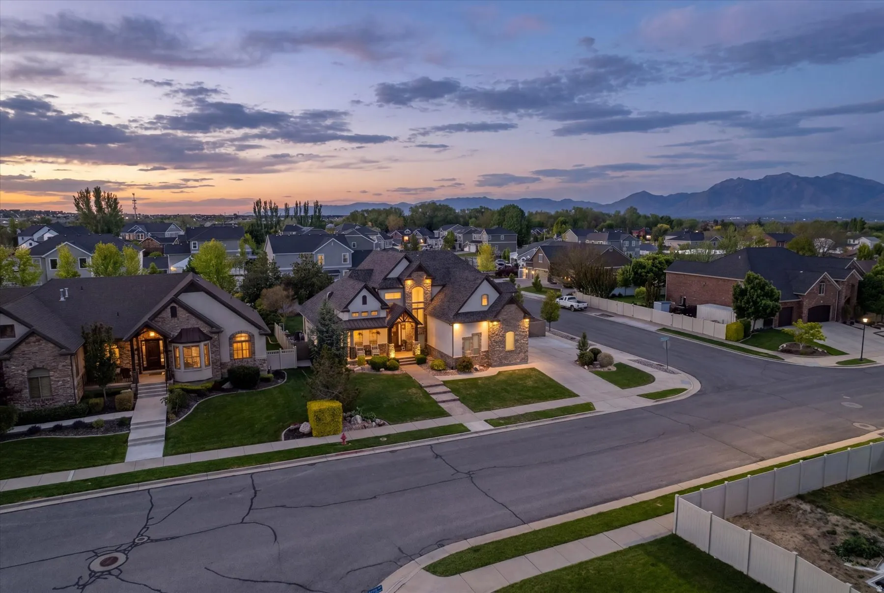 Spacious corner lot residence featuring a multi-gable roofline, stone and siding exterior, and a covered front porch