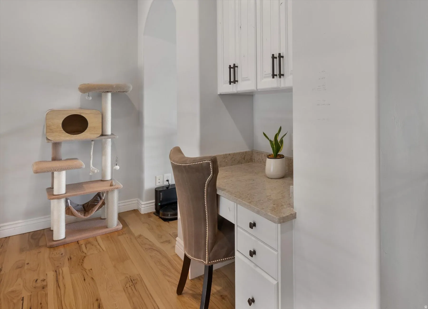 Flex loft space with Integrated desk area featuring white cabinetry with dark hardware, a speckled countertop, and wood-finish flooring