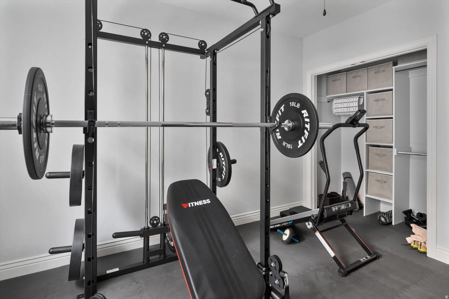 Dedicated fitness space featuring rubberized flooring and a built-in closet with shelving and hanging rods