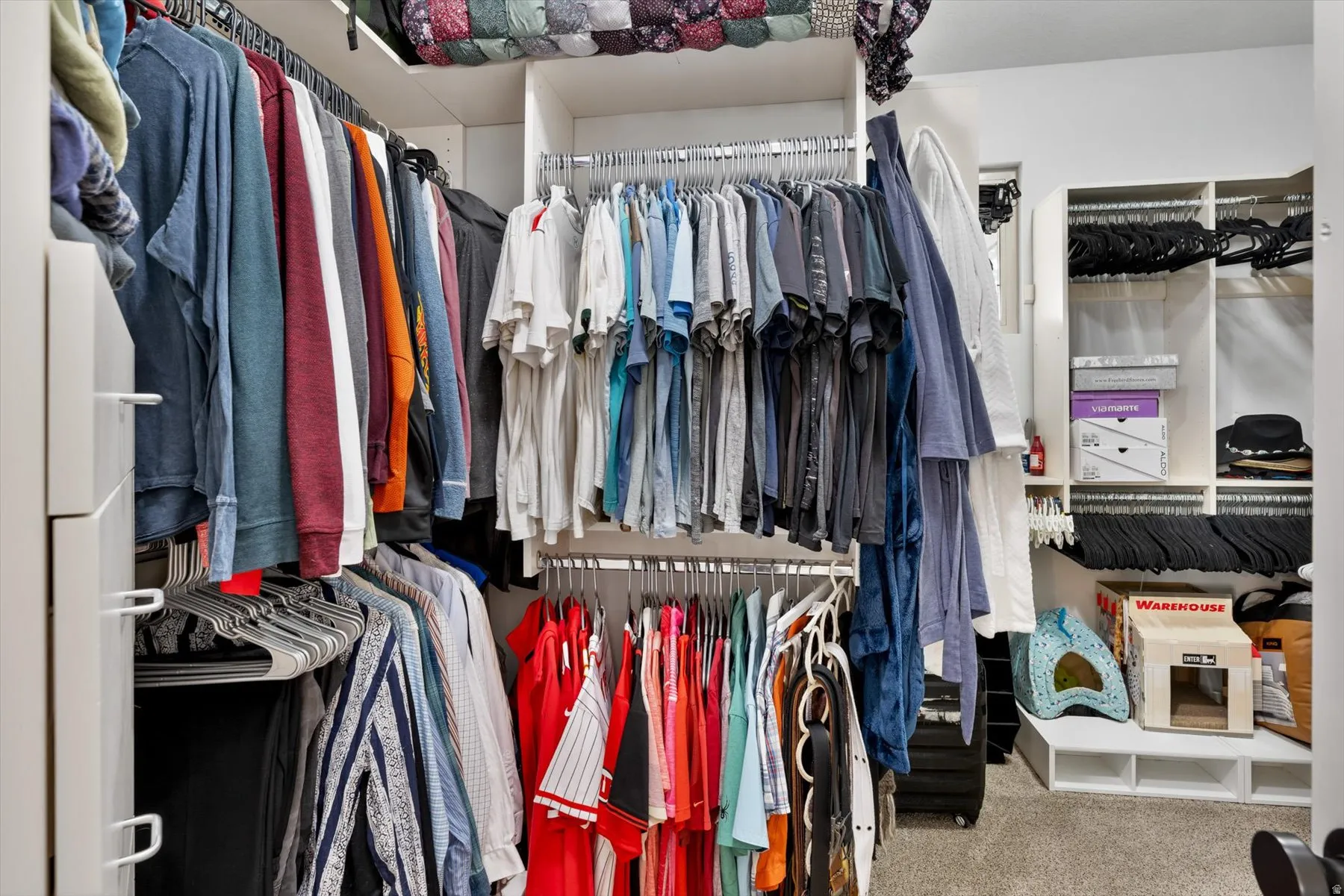 Primary bedroom custom walk-in closet system featuring multiple hanging rods, integrated shelving, and white cabinetry