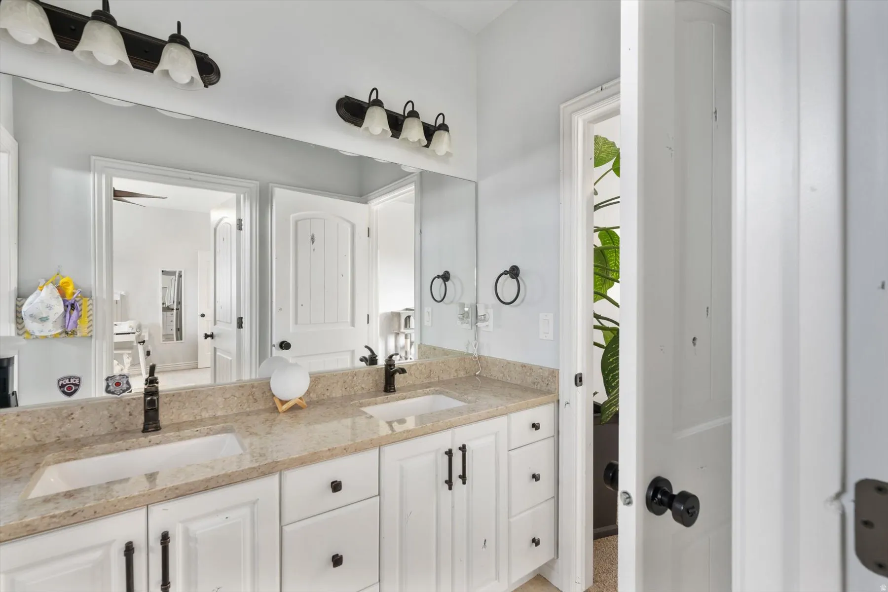 Full bathroom vanity featuring dual undermount sinks, a light-toned countertop, and white cabinetry with dark hardware