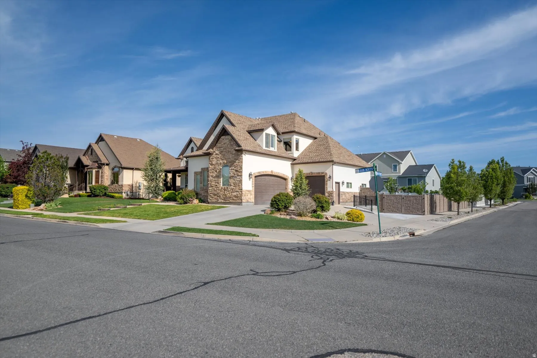 Stately residence with a stone and stucco facade, featuring a prominent gabled roofline and an attached three-car garage
