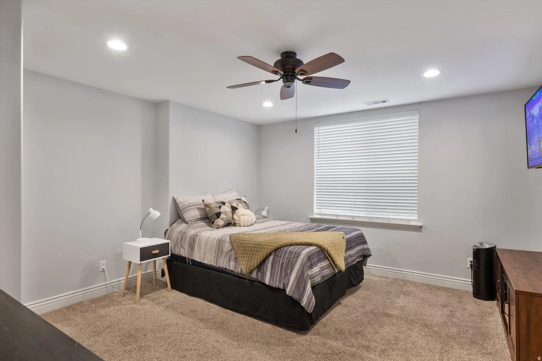Carpeted bedroom featuring a ceiling fan, recessed lighting, and a window with blinds