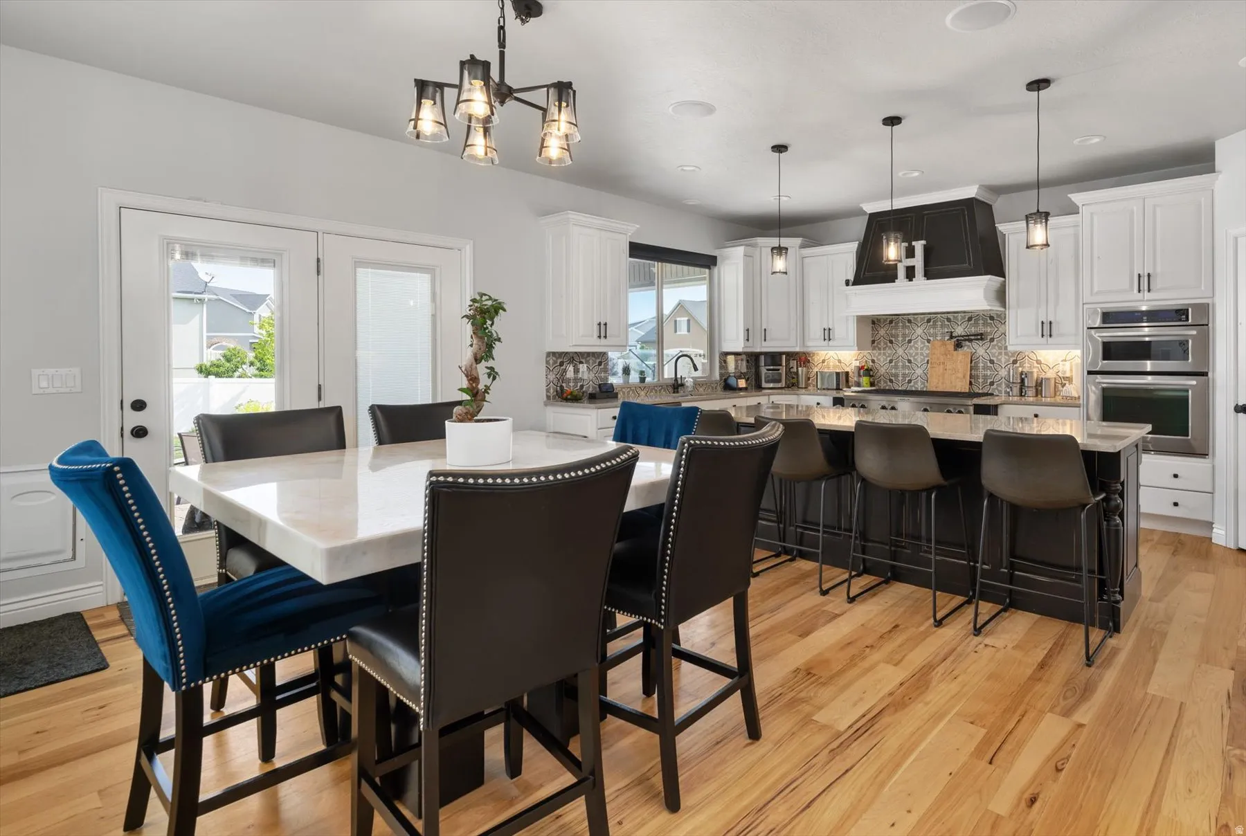 Open-concept kitchen and dining area featuring light-toned wood flooring, white cabinetry, and a dark-toned kitchen island with bar seating