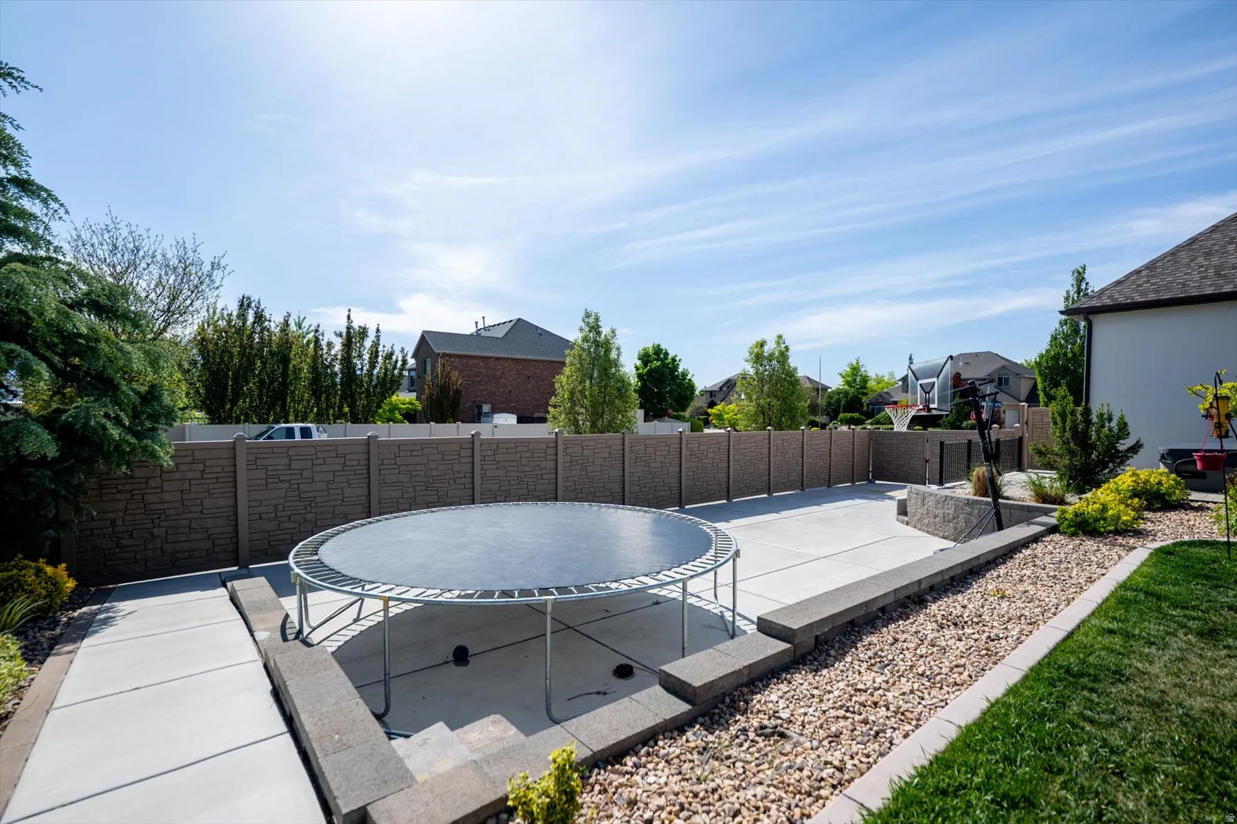 Expansive backyard featuring a concrete patio, decorative rock landscaping, and a substantial privacy fence