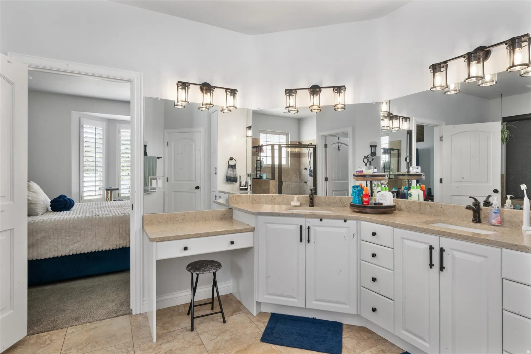 Spacious primary bathroom ensuite featuring an extended double vanity with integrated sinks, ample counter space, and white cabinetry with dark hardware