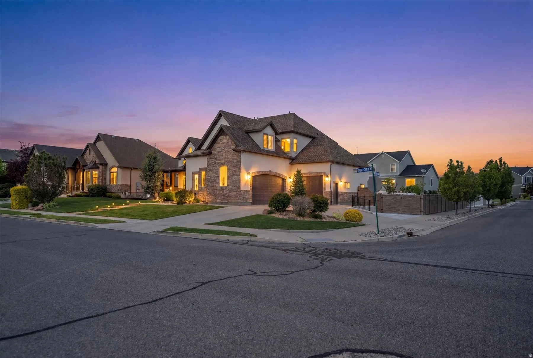 Stucco and stone exterior featuring a multi-gable roofline and integrated three-car garage