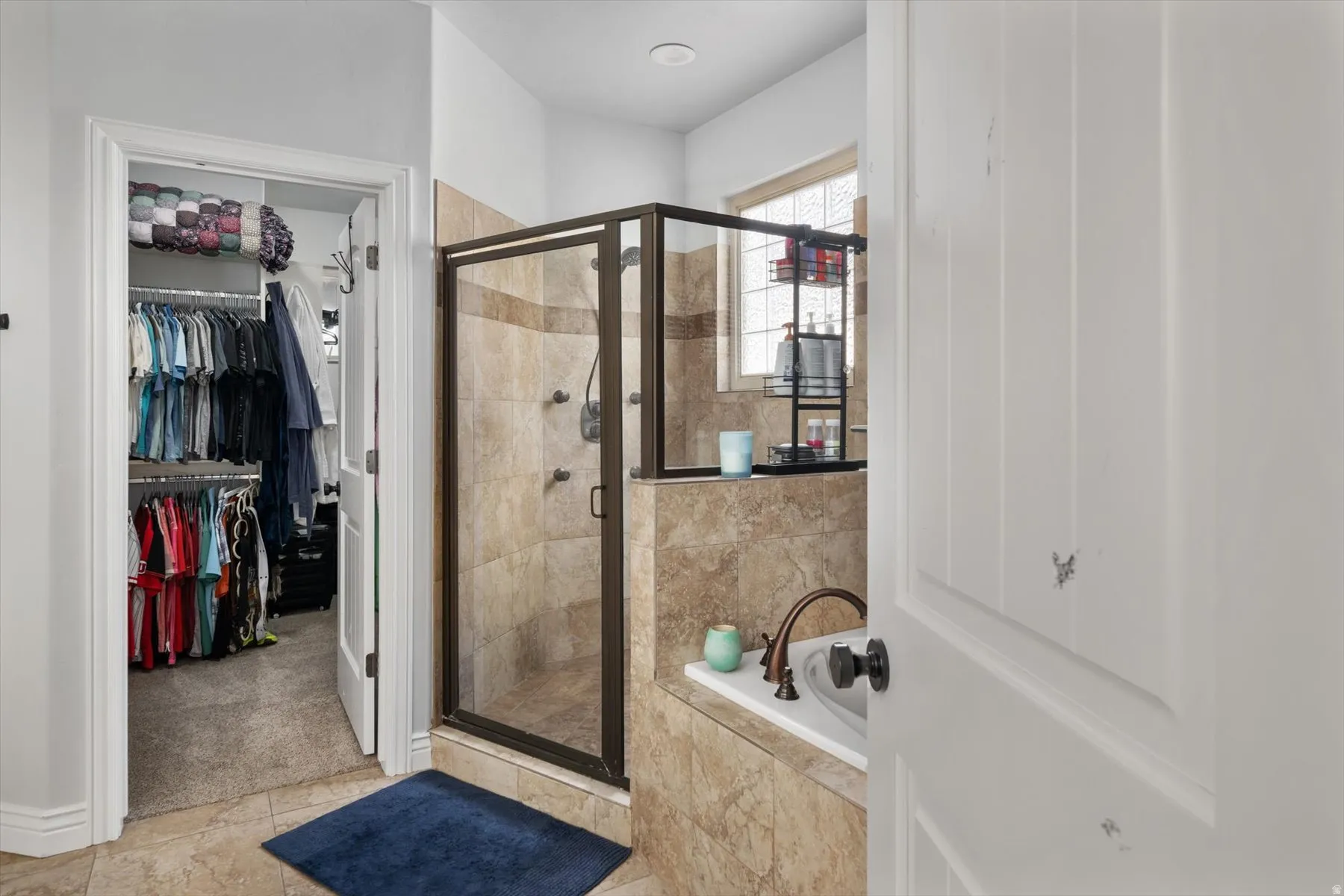 Primary bathroom ensuite with tiled shower enclosure with bronze-finish frame and fixtures, featuring a built-in bench