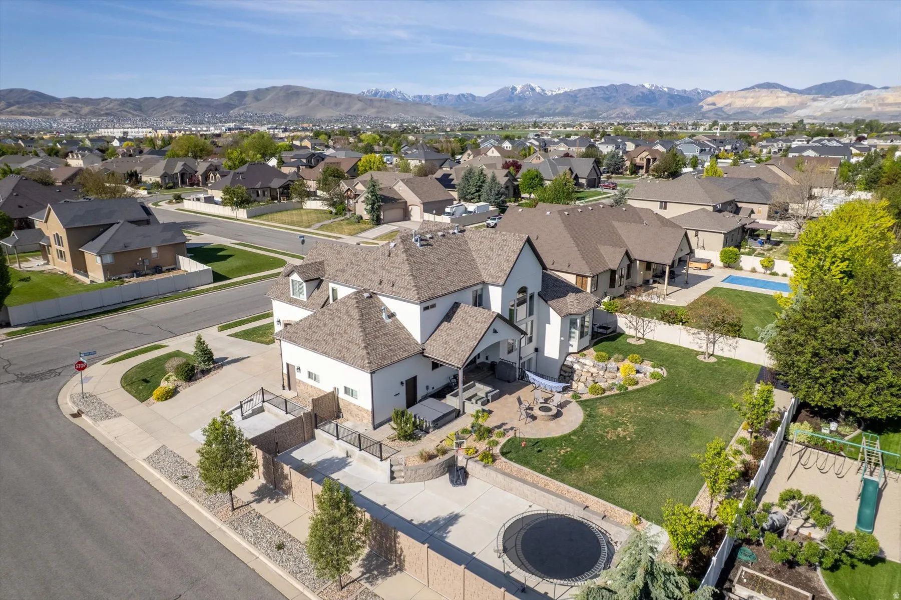Expansive residential property featuring a large green lawn, a covered patio with outdoor seating, and a paved patio area