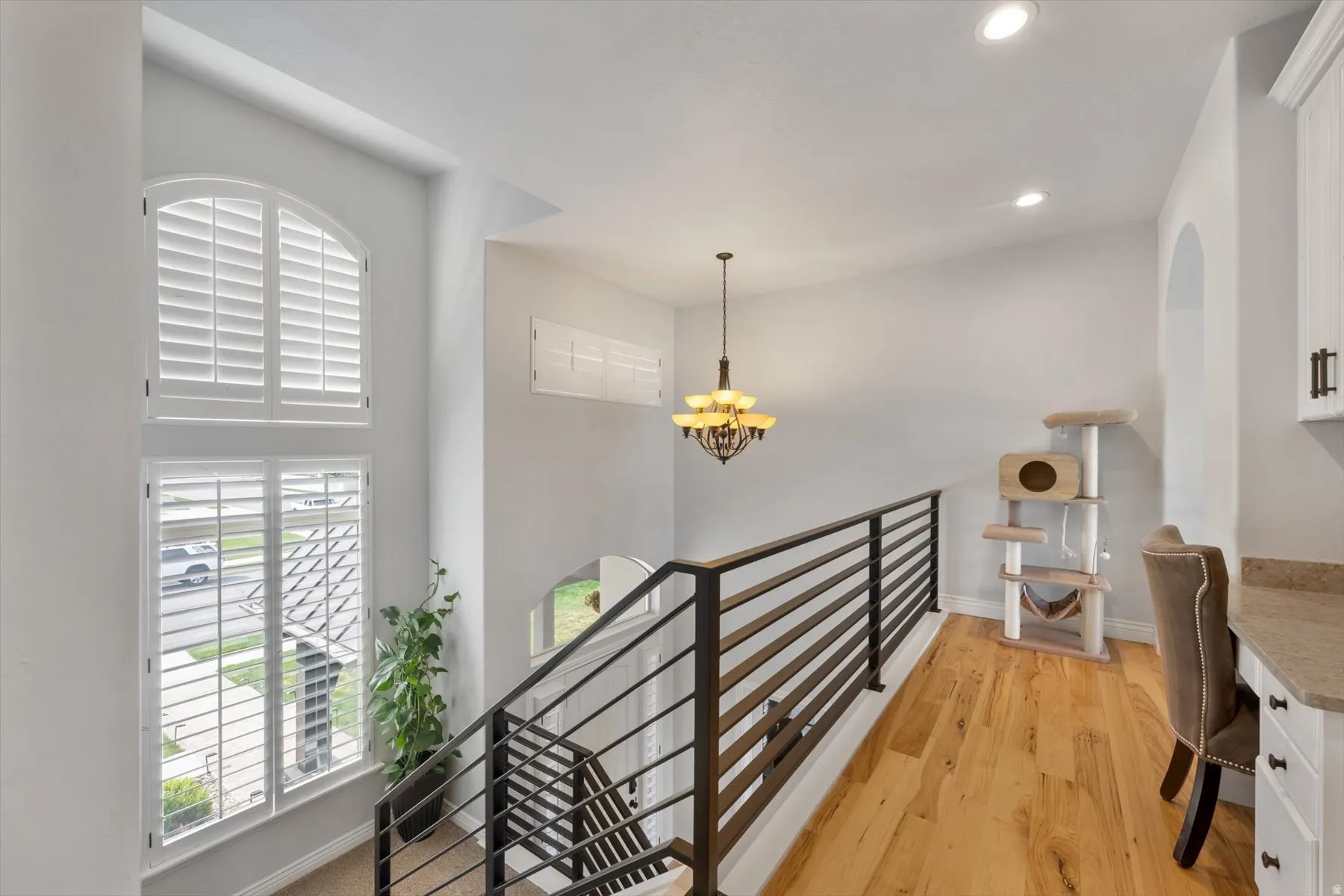 Flex loft space featuring wood-finish flooring, a contemporary chandelier, recessed lighting, and a built-in desk with white cabinetry and a stone-look countertop