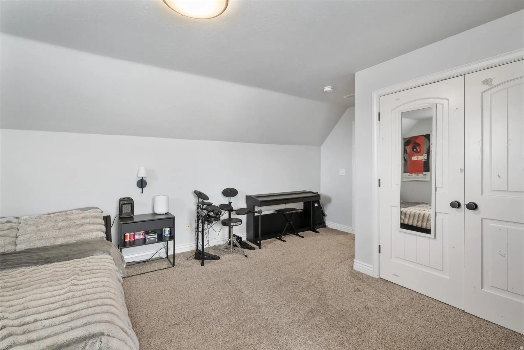 Carpeted bedroom featuring a sloped ceiling, recessed lighting, double white panel doors with black hardware, and a wall-mounted sconce