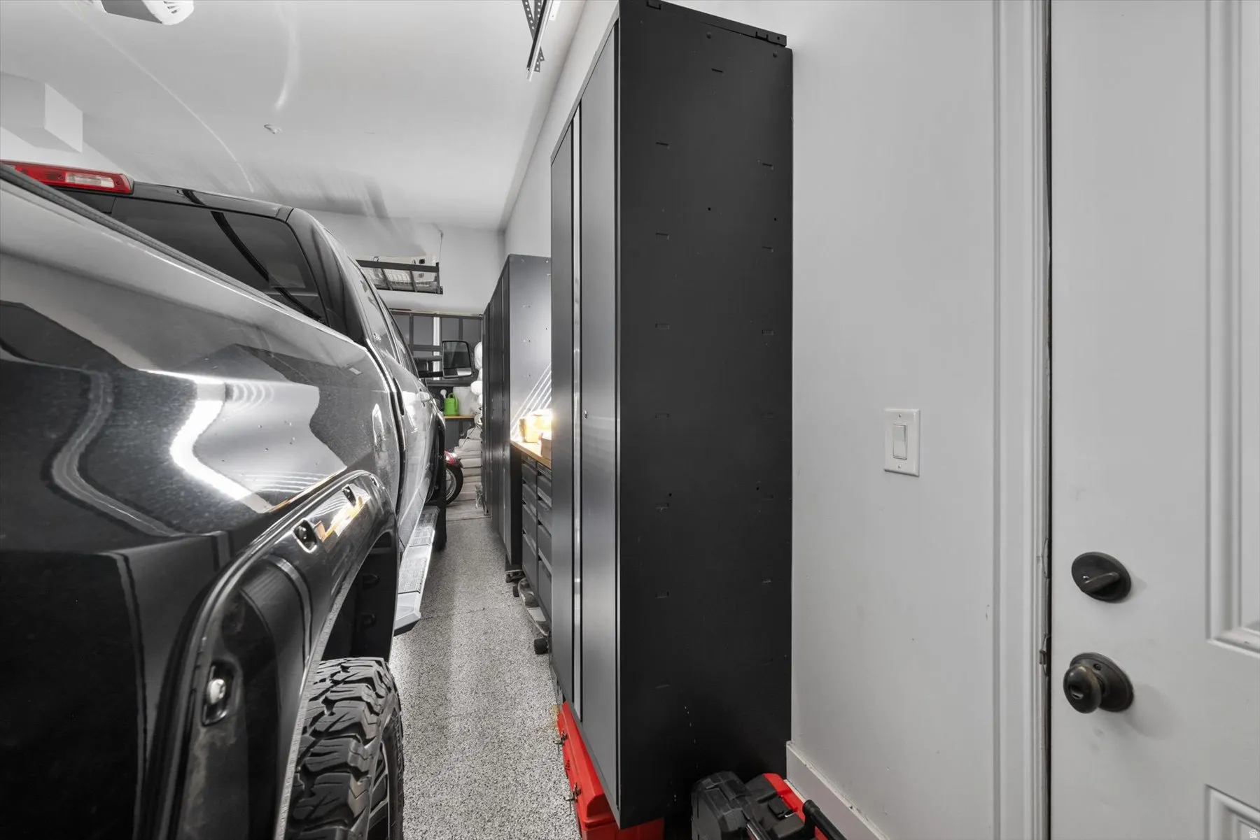 Garage featuring a durable speckled floor, bright overhead lighting, and built-in storage cabinetry