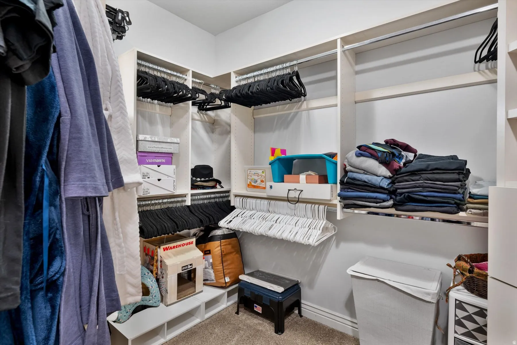 Primary bedroom custom walk-in closet system featuring multiple hanging rods, integrated shelving, and corner storage