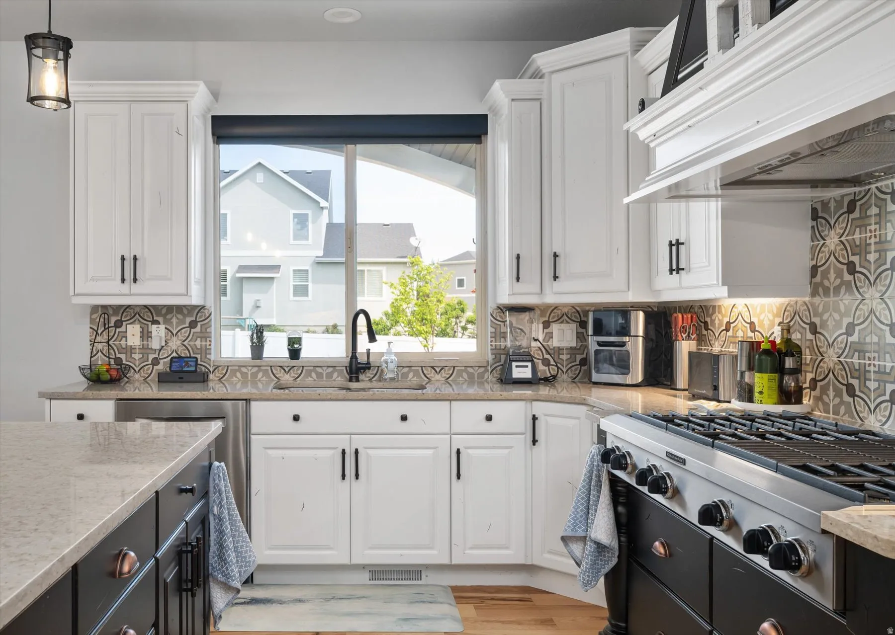White cabinetry with dark hardware, stone countertops, and an ornate tile backsplash