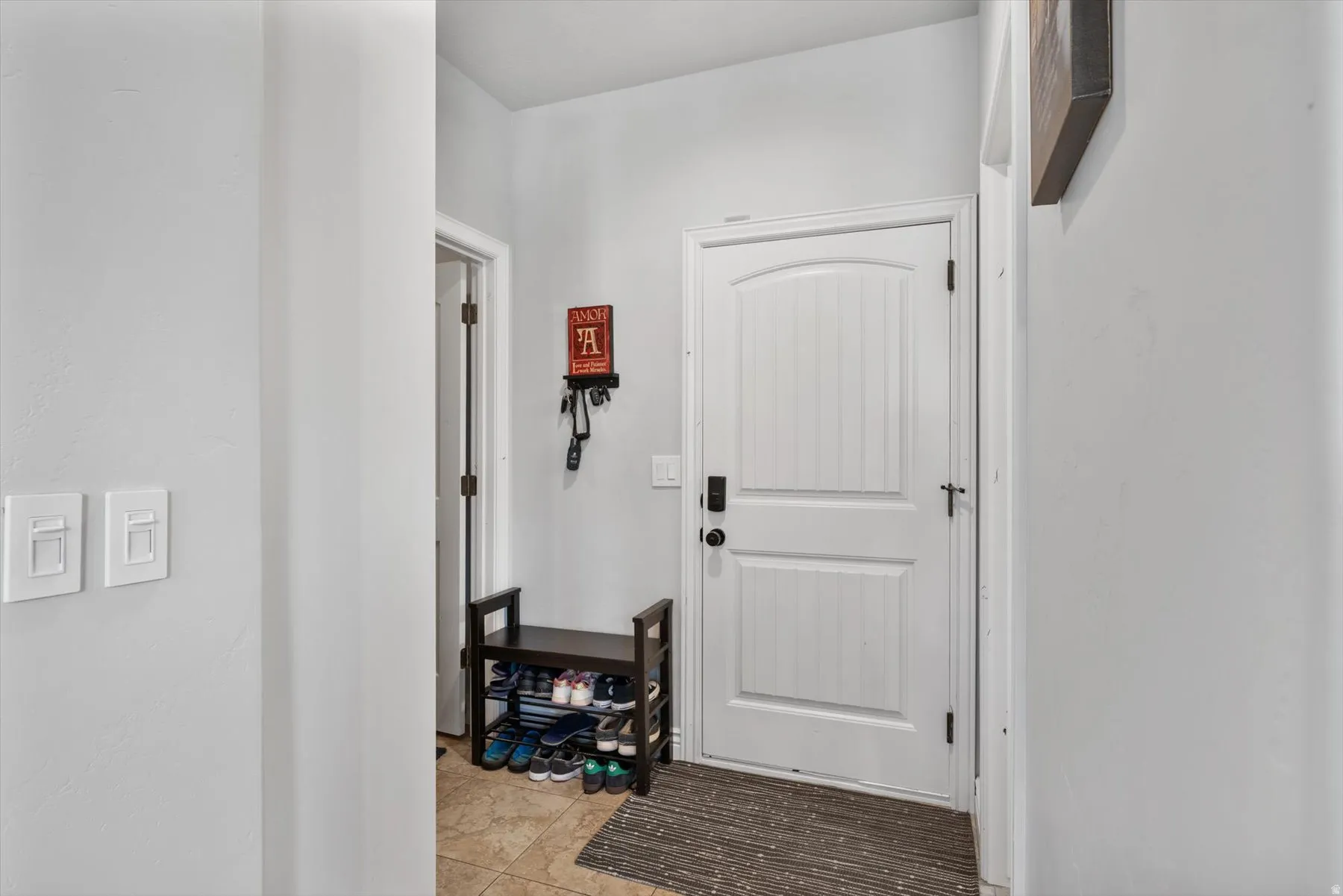 Mudroom area off the garage with white paneled door featuring a smart lock system