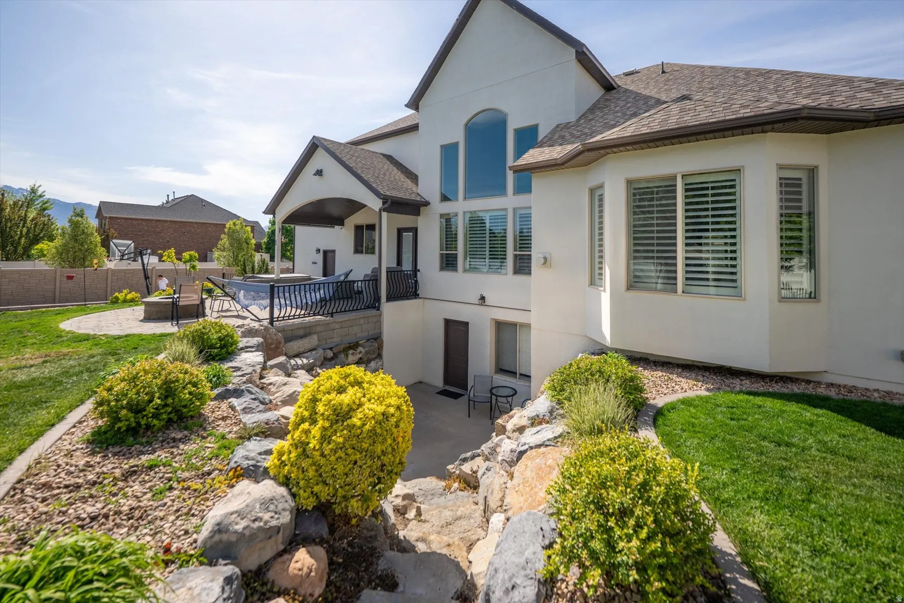 Expansive backyard with multi-level landscaping, featuring a private patio, tiered retaining walls, and a separate fire pit area
