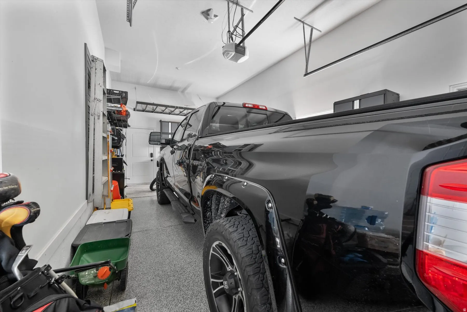 Spacious garage with epoxy flooring, white walls, and overhead garage door opener
