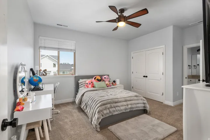 Carpeted bedroom featuring a ceiling fan, a window with blinds, and white double closet doors