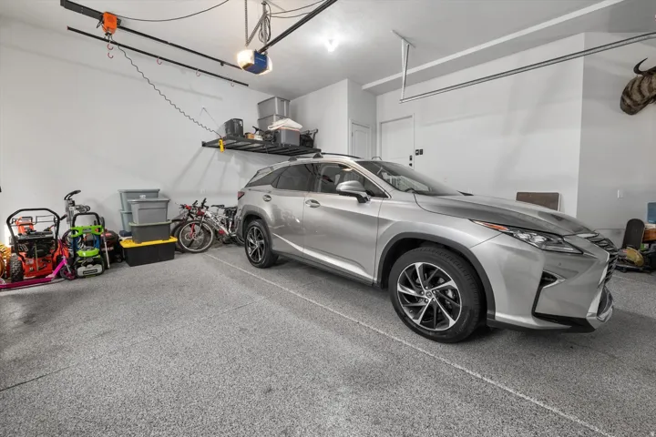 Spacious garage featuring a durable epoxy-coated floor, ample wall-mounted storage shelving, and a built-in garage door opener