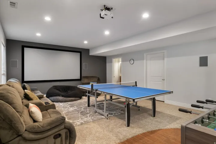 Dedicated entertainment room featuring a large projection screen, recessed lighting, and a neutral color palette